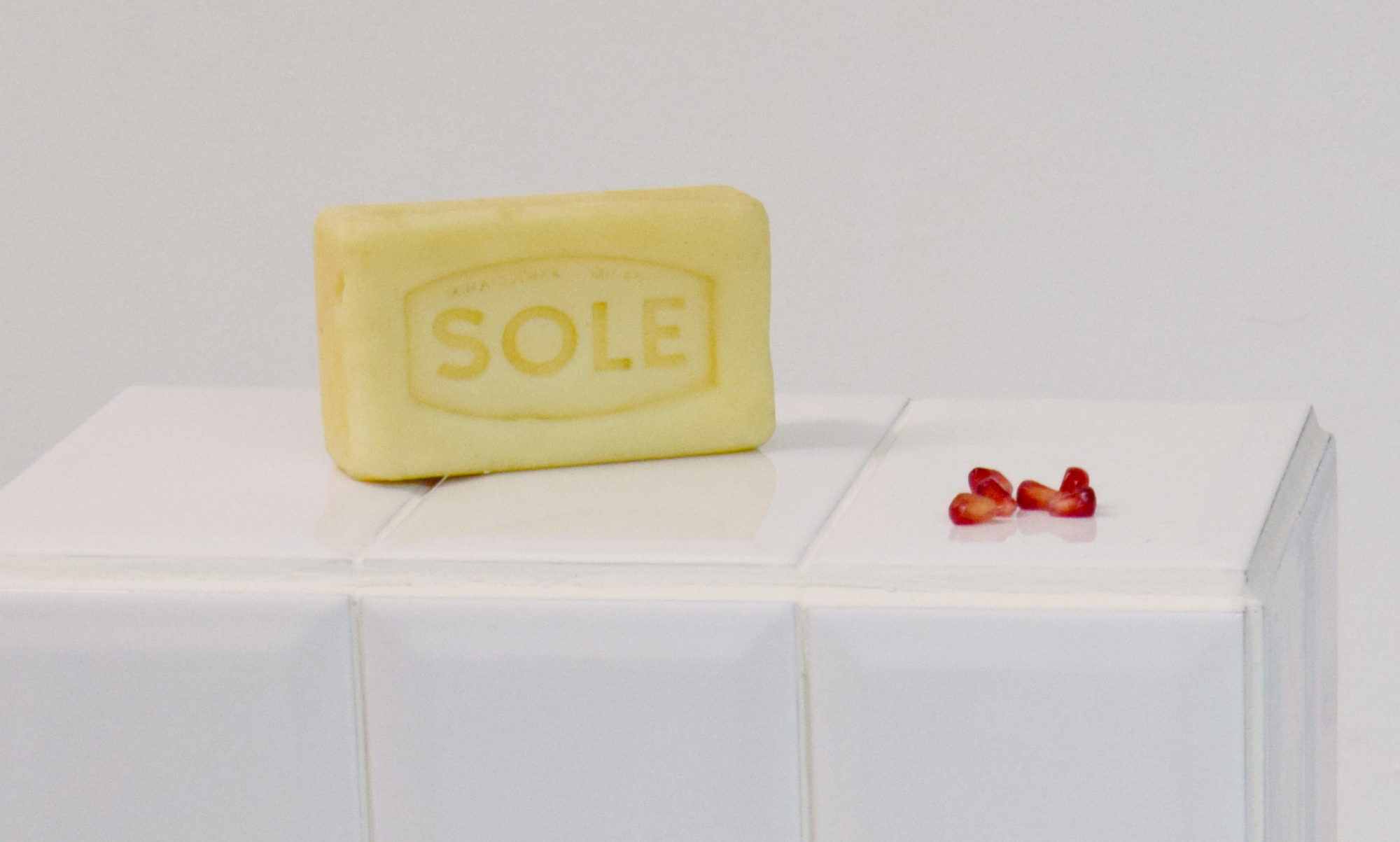 Glass soap and glass pomegranate on tiled plinth.